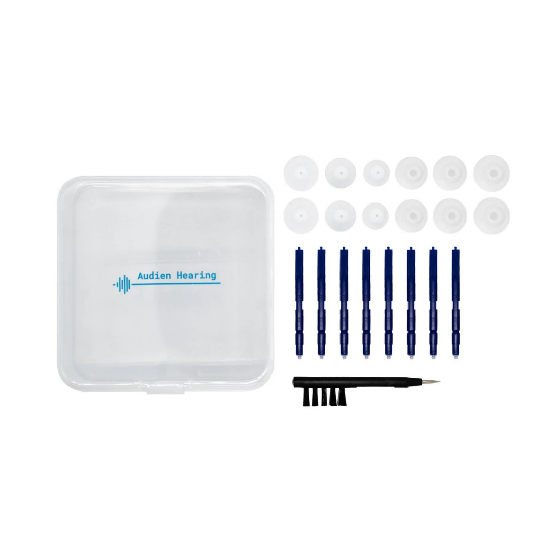 The Audien Maintenance Kit For Hearing Aids includes a clear case, 8 blue cleaning brushes, a black tool, small brush, and 10 white ear domes—everything neatly organized for Atom Pro 2 users. Perfect for easy hearing aid care.